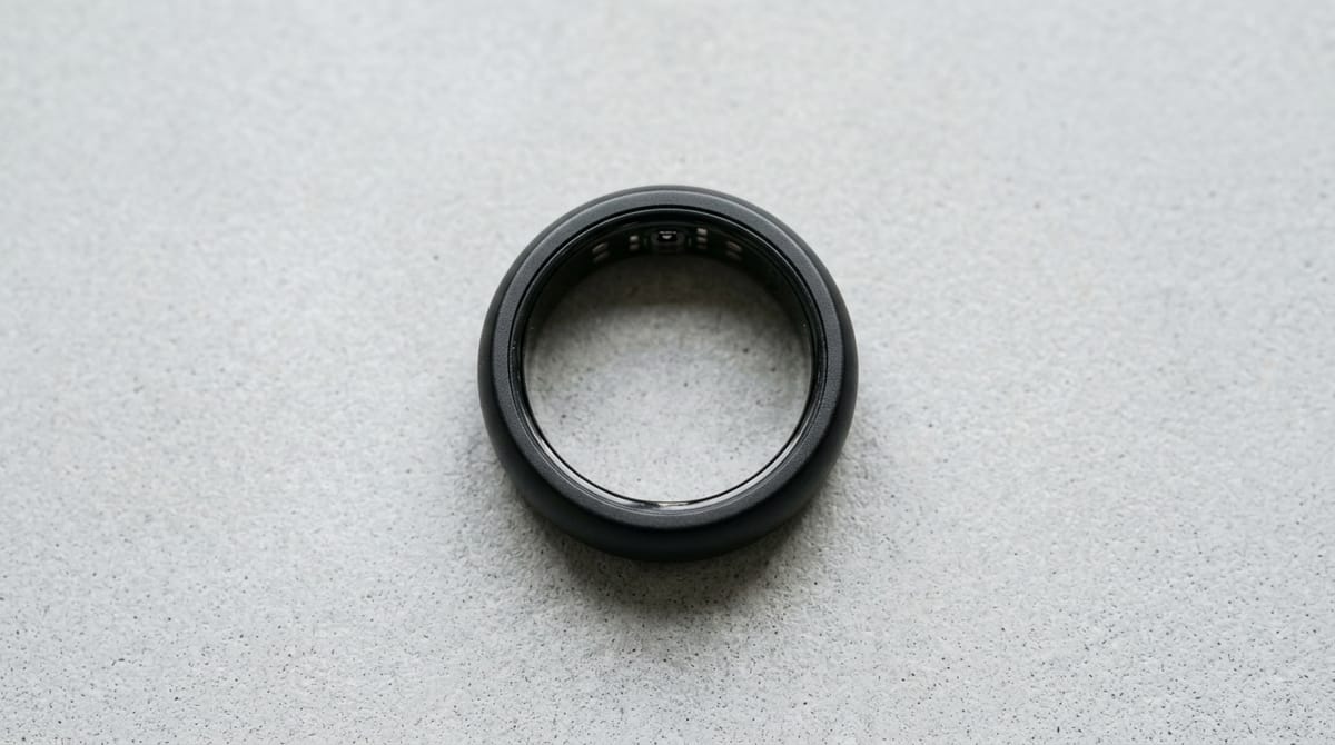 Flat lay of a plain black smart ring on light grey