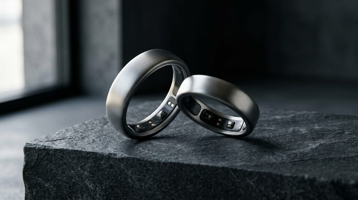 Two titanium smart rings angled on a graphite plinth